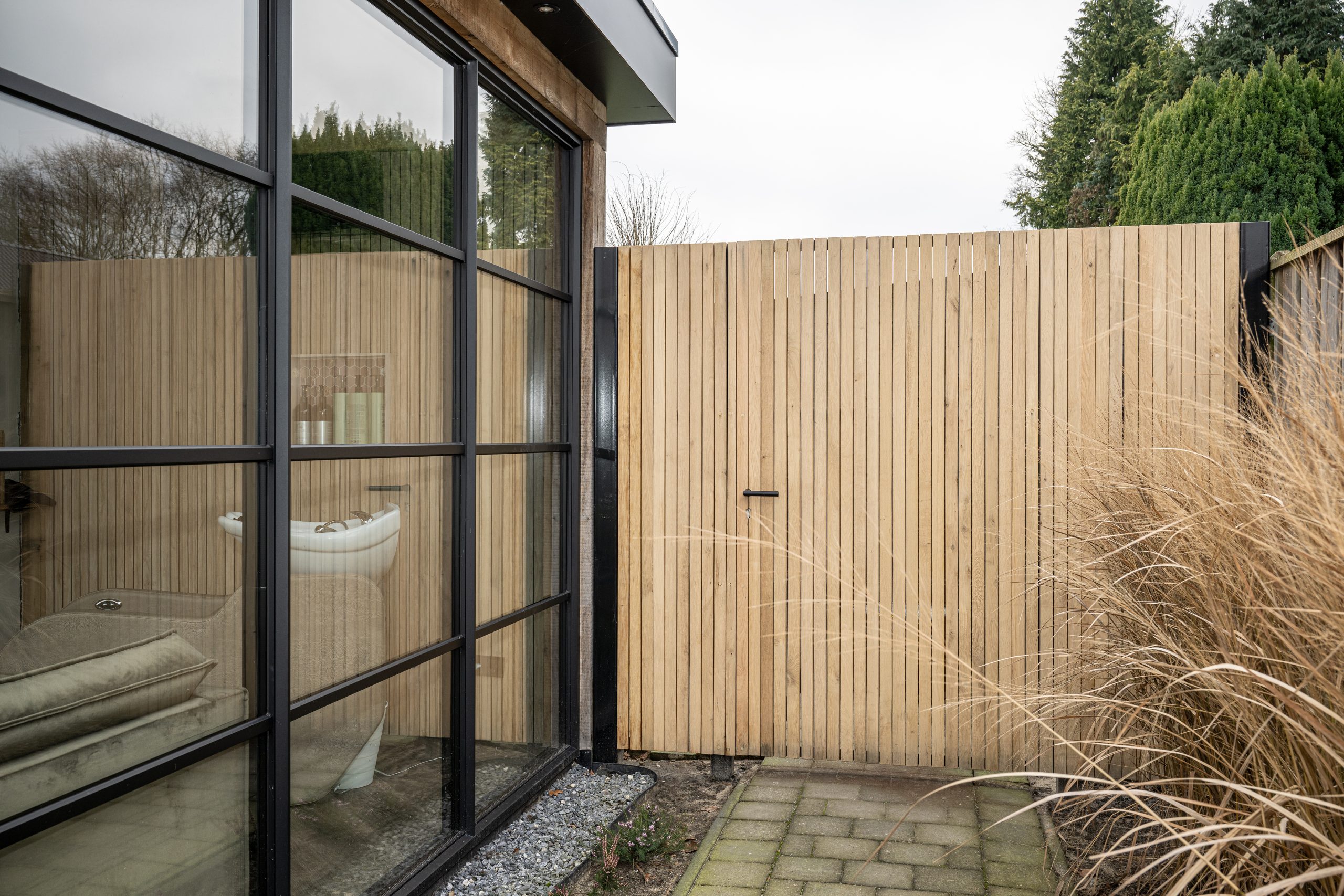 Verborgen poort met latjes in tuin, passend bij overkapping