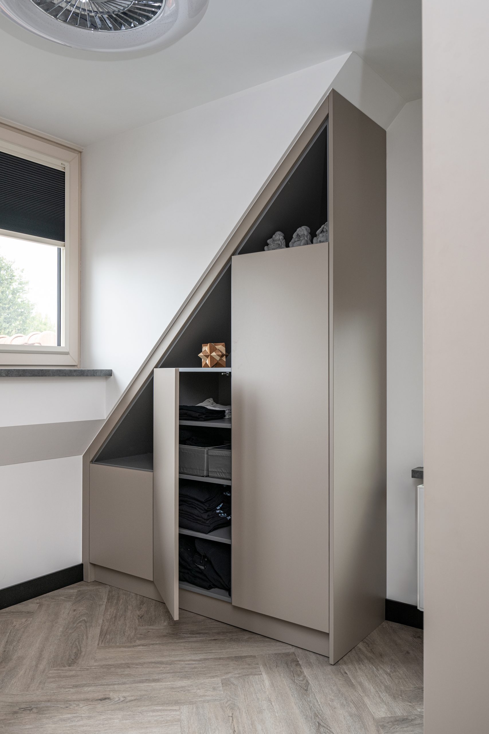 Beige inbouwkast op maat geplaatst onder een schuine kant in de slaapkamer