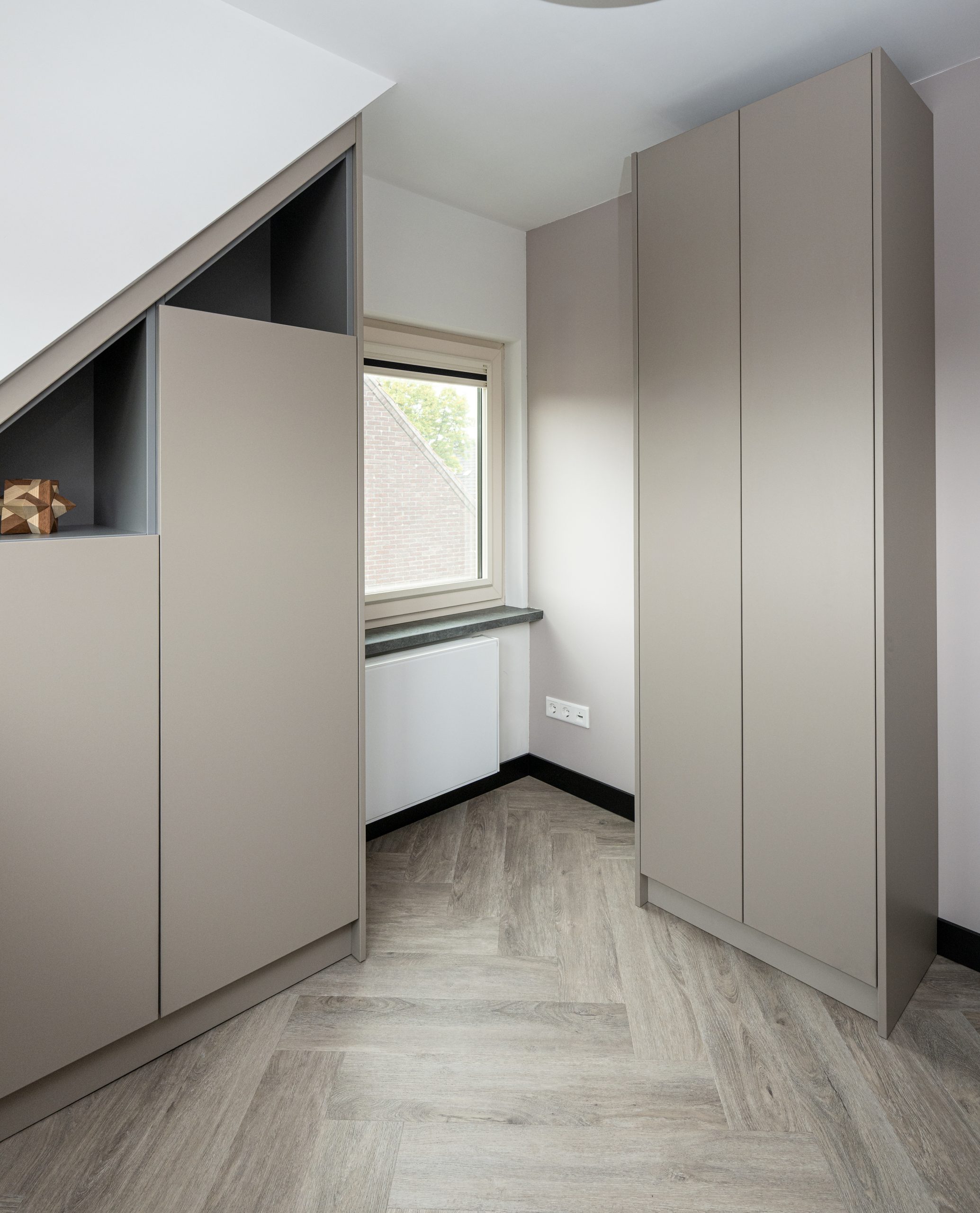 Beige kledingkast met open vakken voor decoratie en opbergruimte onder schuine wand