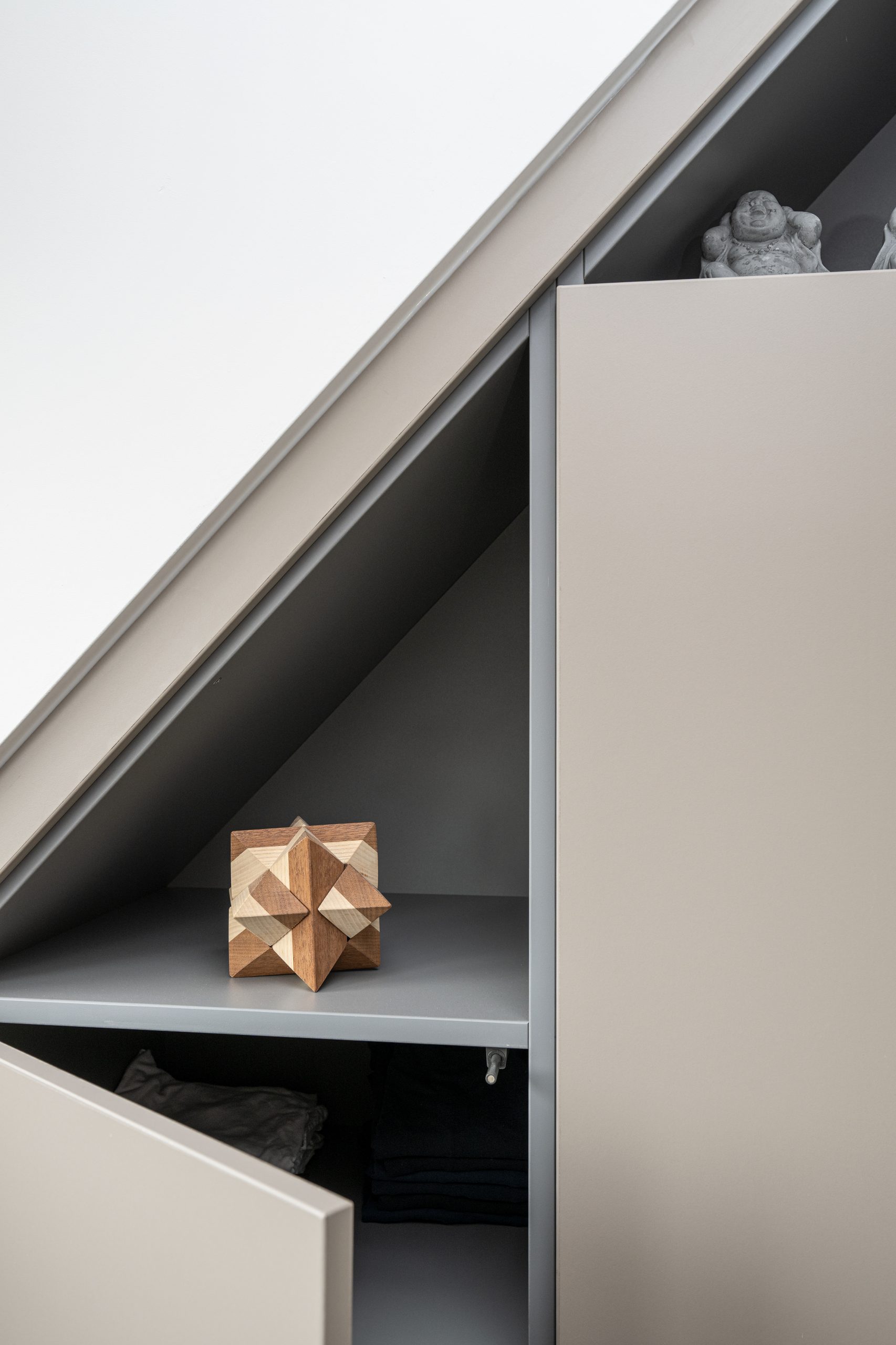 Beige kledingkast onder schuin dak, ideaal voor gebruik op zolder of in kleine ruimtes