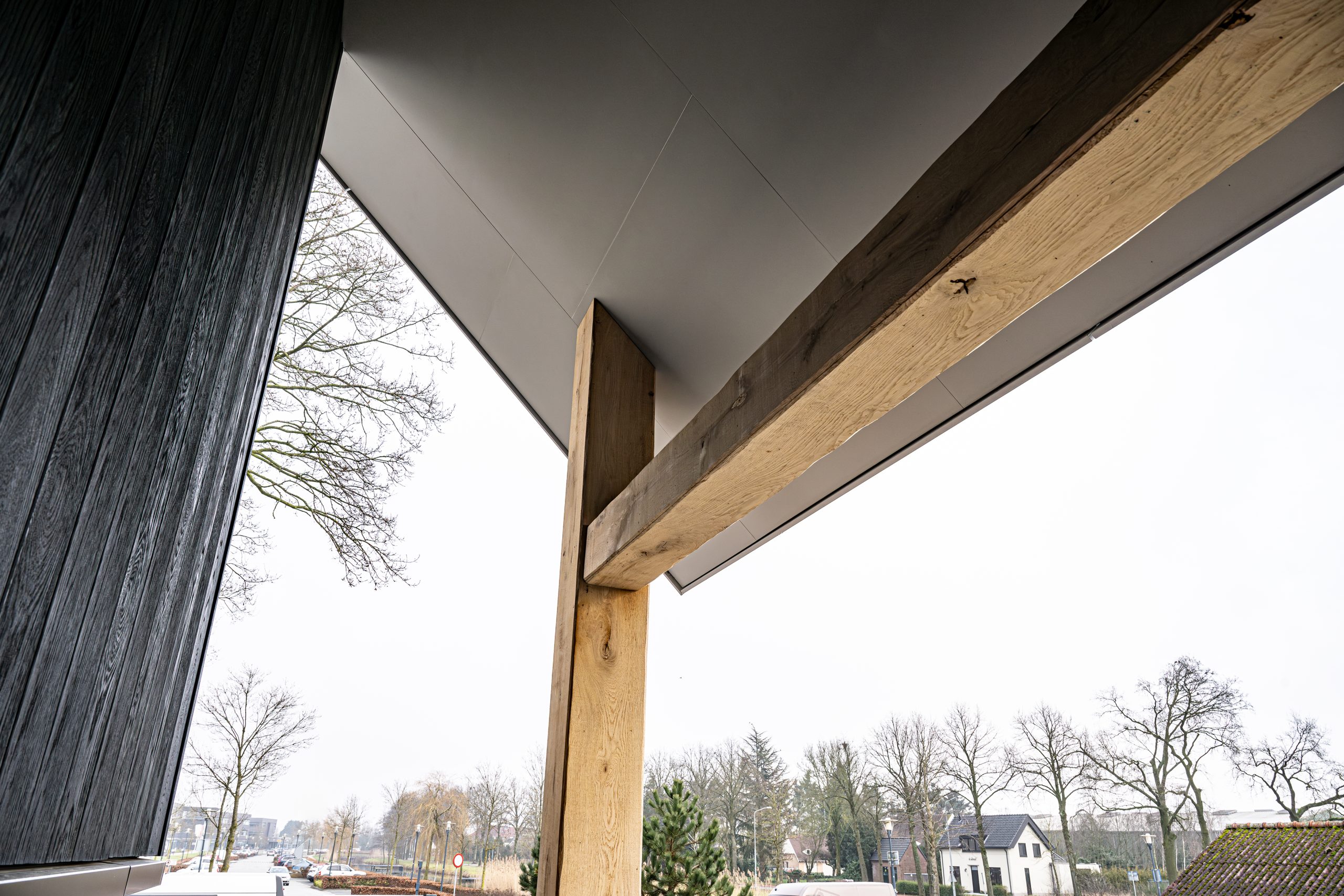 Onderzijde van een overkapping waarbij de stalen draagconstructie stijlvol is bekleed met authentieke eikenhouten balken.