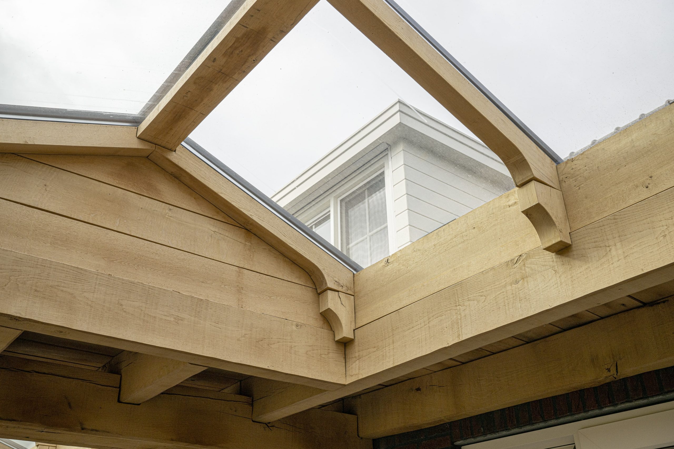 Detail van de hoogwaardige houtverbindingen en de afwerking van de glazen lichtstraat in een eikenhouten dak.