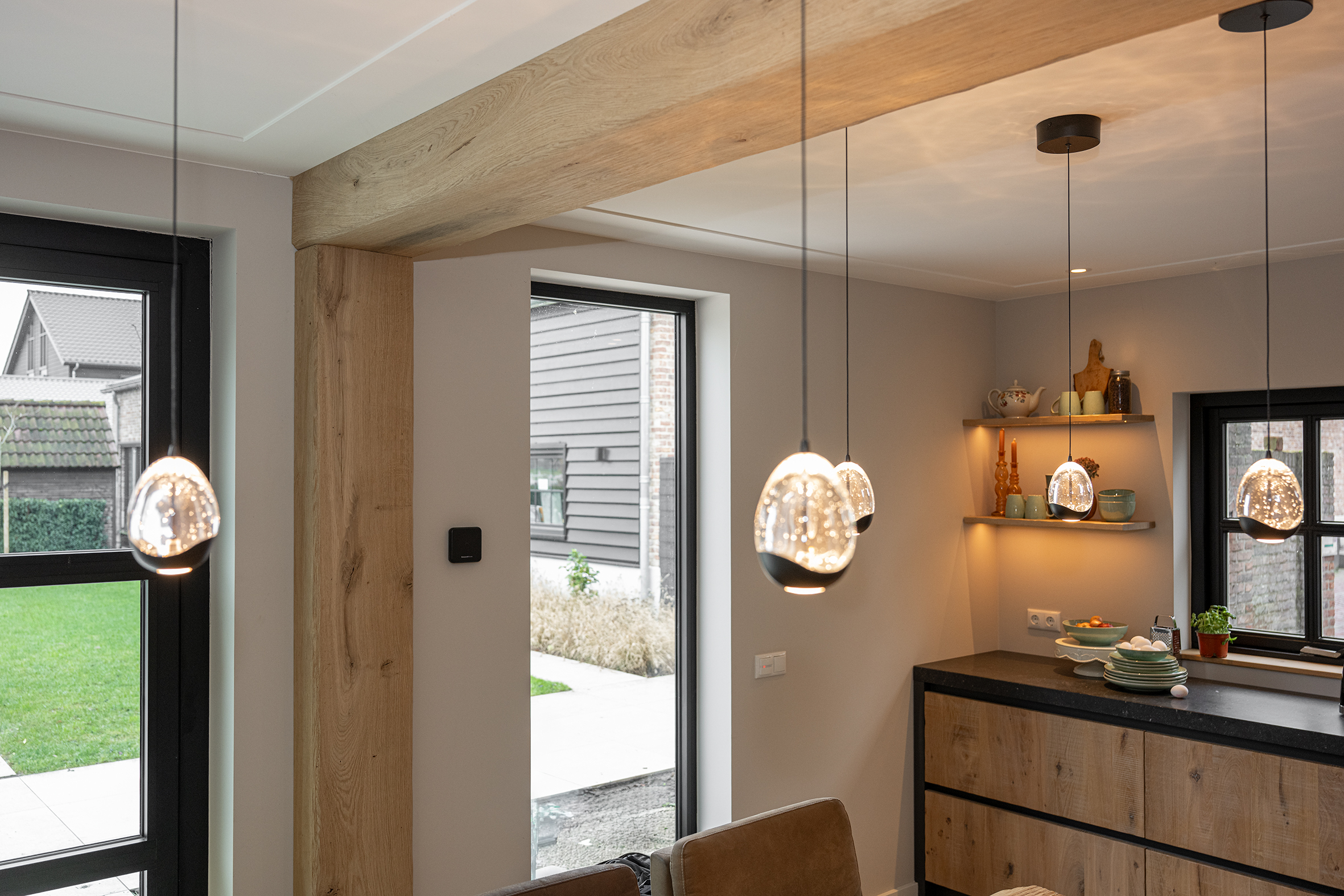 Luxe landelijke eetkamer met een robuuste boomstamtafel, design hanglampen en een eikenhouten balkenplafond.