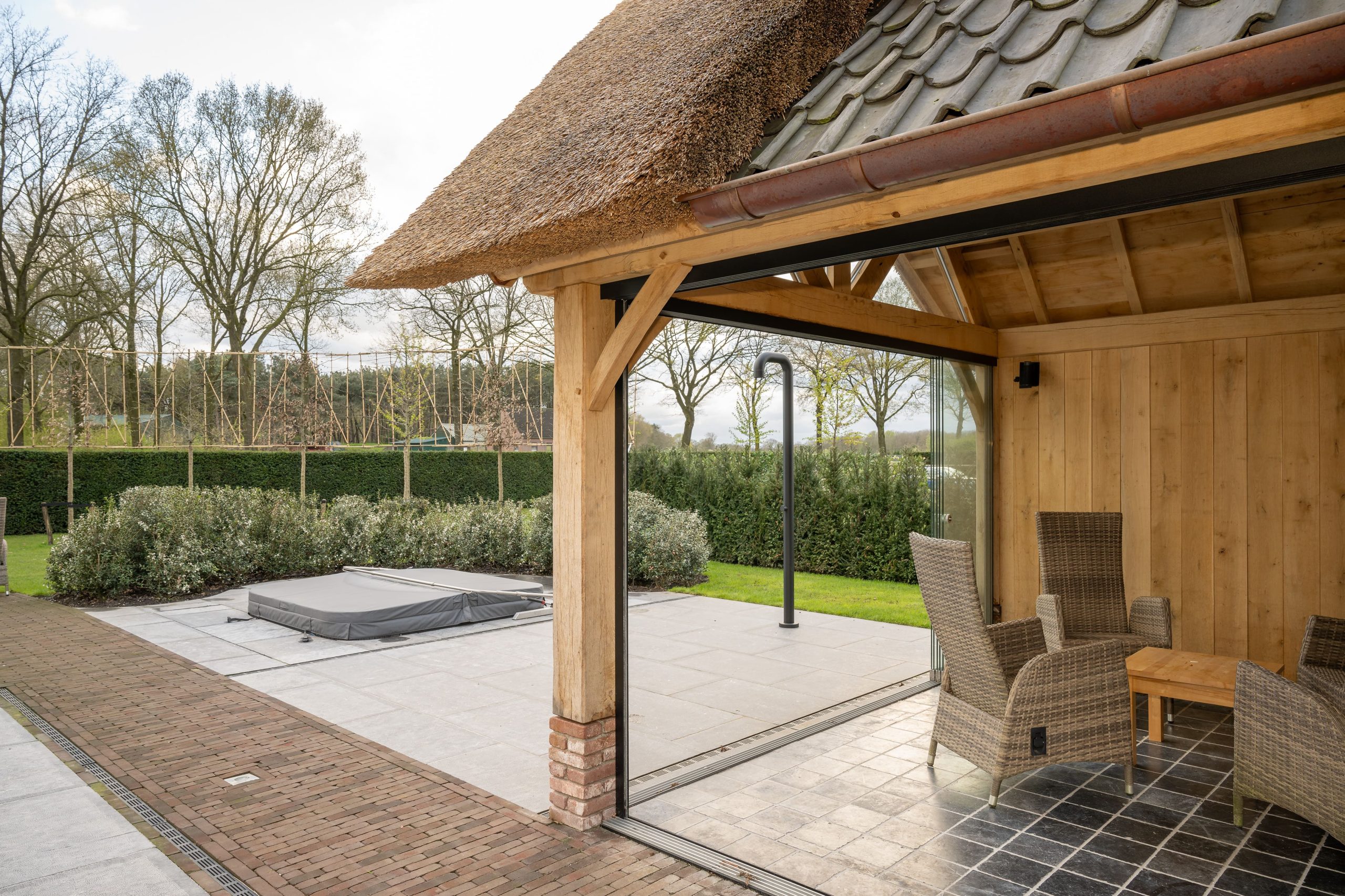Uitzicht vanuit een houten buitenverblijf op een terras met jacuzzi en zwembad.