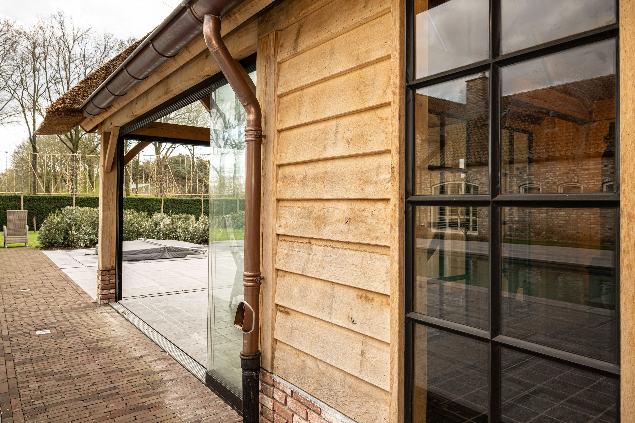 Zwart stalen ramen gecombineerd met horizontale eikenhouten gevelbekleding.