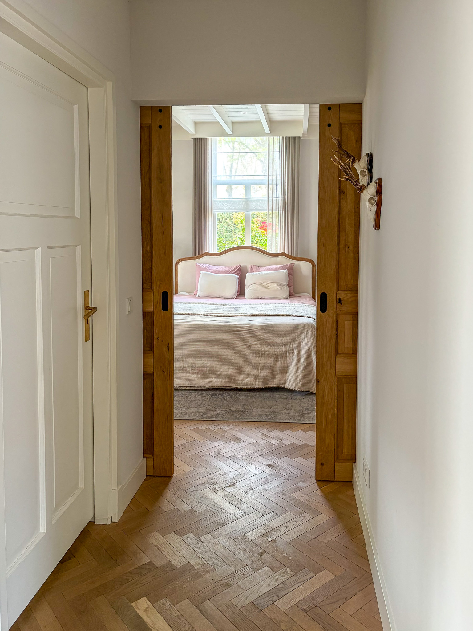 Close-up van het robuuste zwarte stalen schuifdeurbeslag met zichtbare bouten op een massief houten deur.