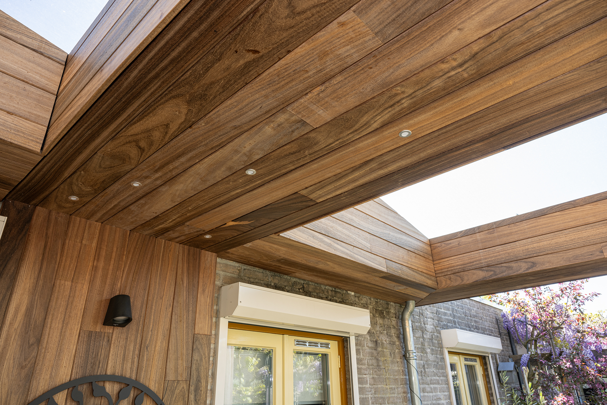 Gecombineerd zicht op het padoek houten plafond met inbouwspots en de grote glazen lichtstraat.