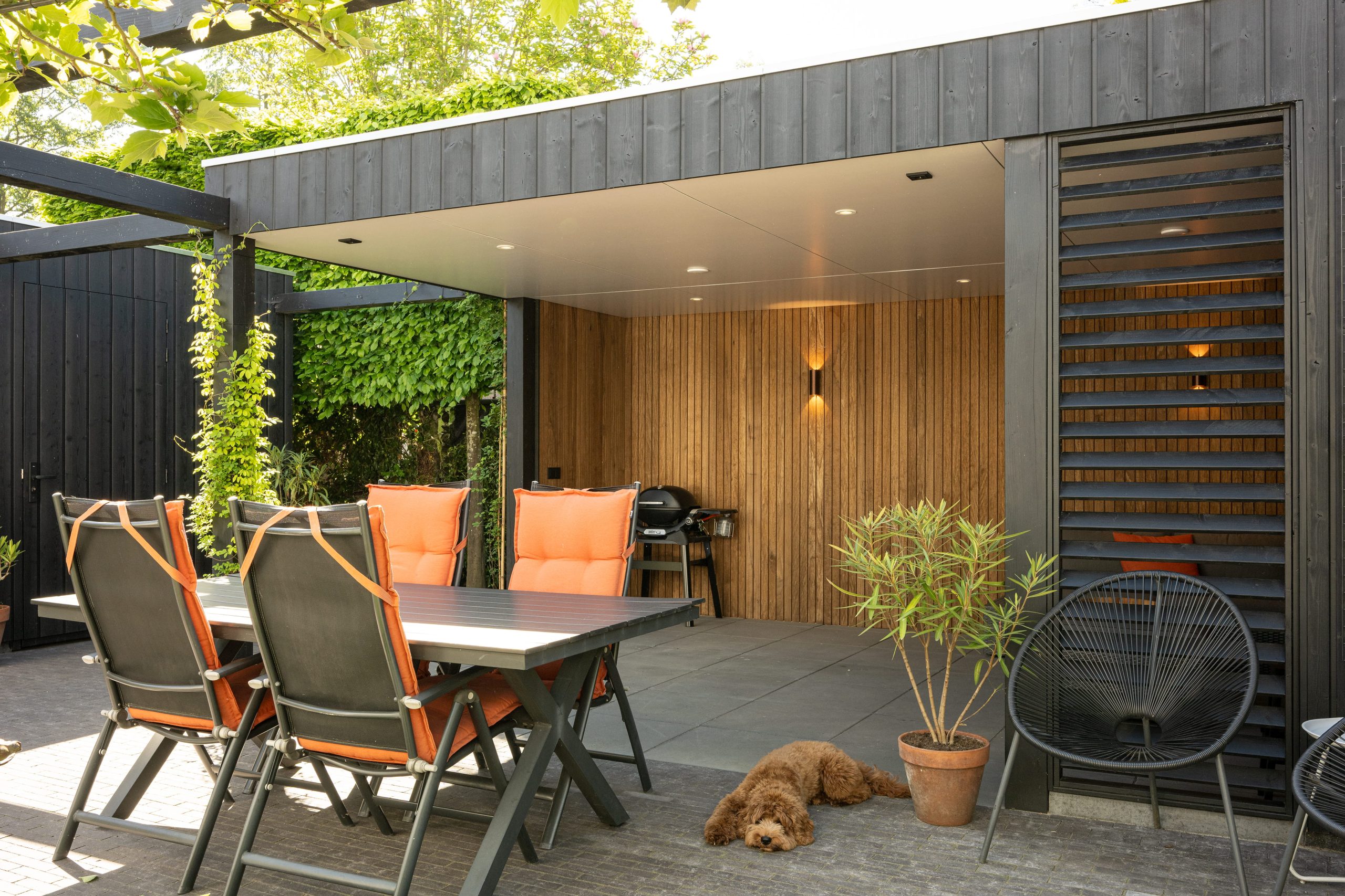Modern terras met een warme thermo fraké achterwand en zwarte houten details.