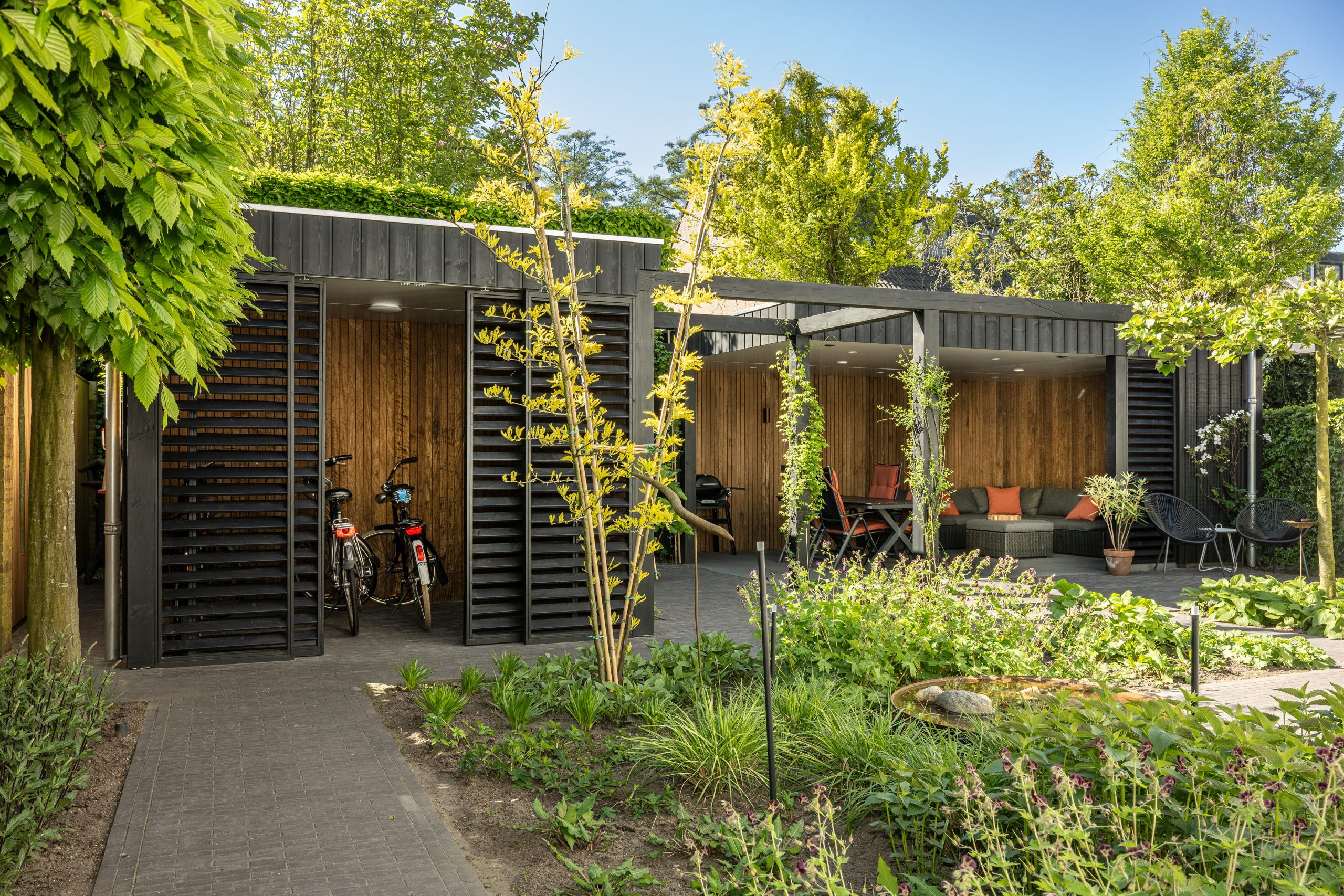 Luxe tuinhuis met zwarte thermo vuren gevel en een overdekt terras afgewerkt met thermo fraké.