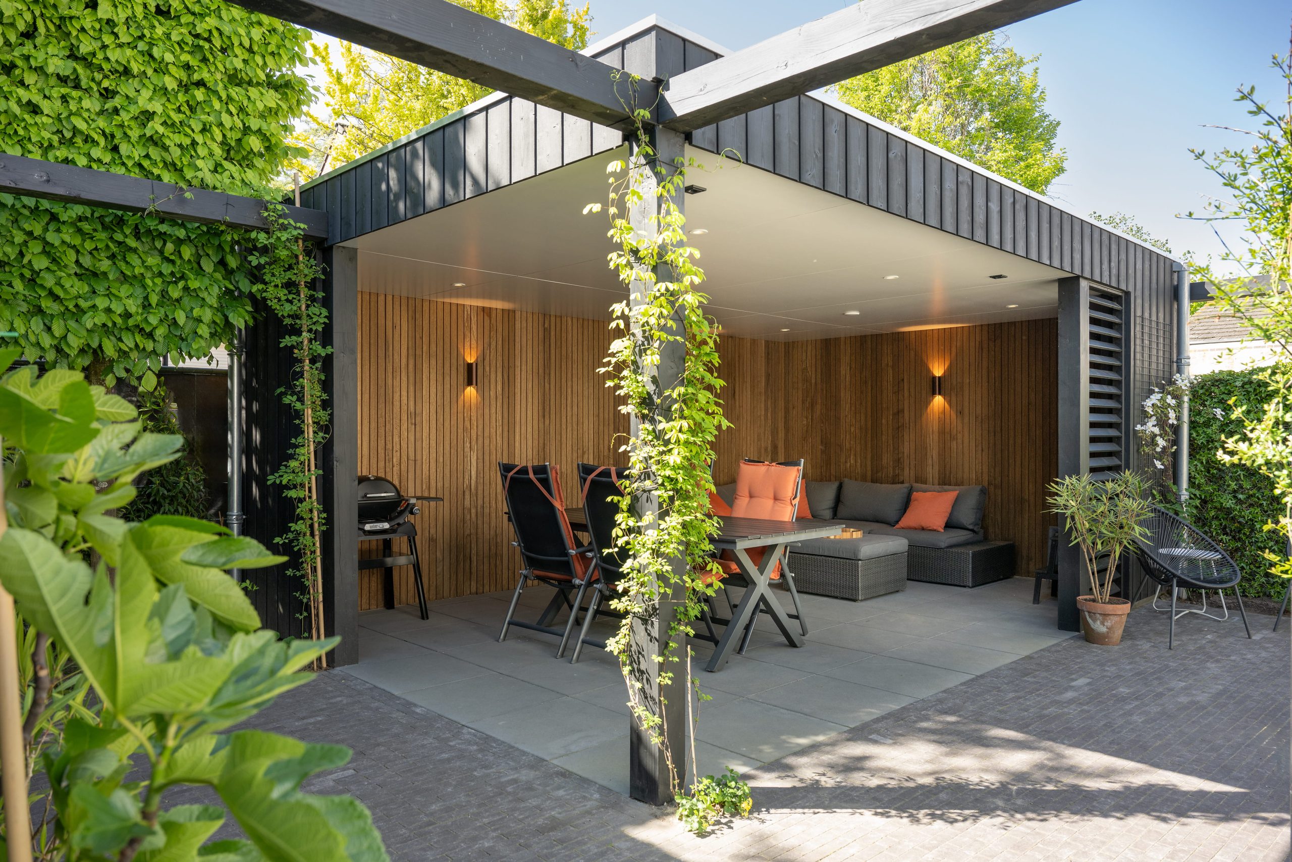 Modern tuinontwerp met een stijlvolle overkapping van thermo fraké hout en zwarte details.